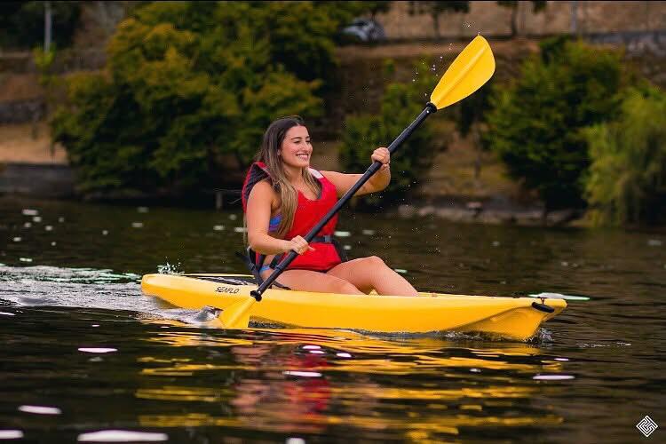 A woman paddling a single yellow kayak on the river