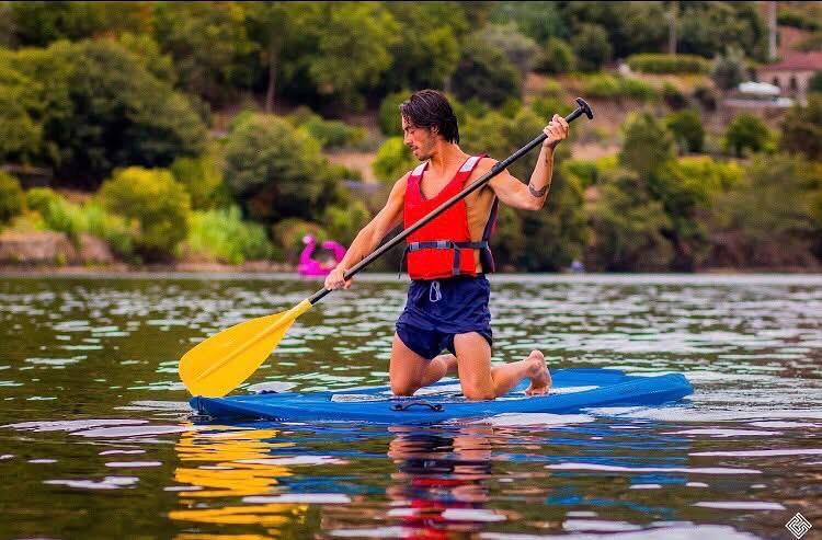 A paddleboarder kneeling on a SUP board on the river